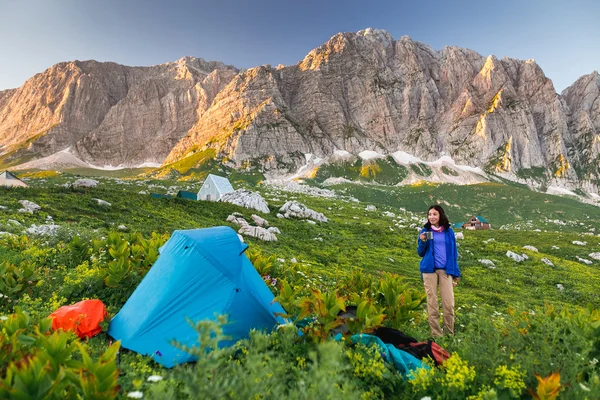 Mulher com uma barraca em um acampamento nas montanhas do Cáucaso com penhascos rochosos no fundo — Fotografia de Stock