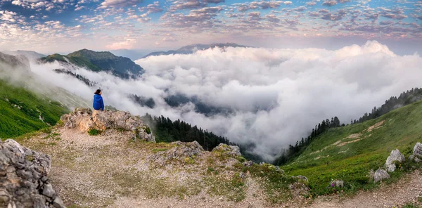 Jovem mulher mochileiro caminhadas no pico da montanha acima das nuvens e neblina — Fotografia de Stock