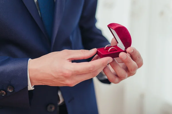 Handen van de bruidegom klaar in pak. Hij is houder van het vak met de trouwringen. — Stockfoto