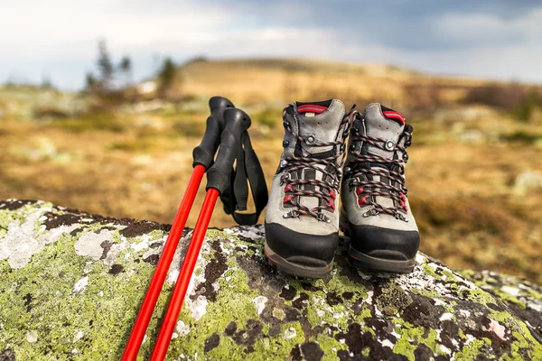 Laarzen en trekking palen op de steen — Stockfoto