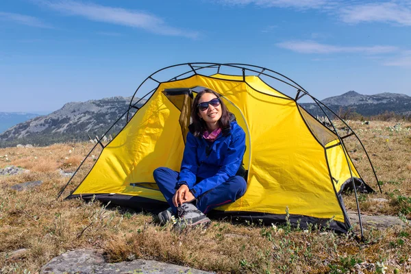 Mulher em viagem de caminhada nas montanhas. Tenda turística no acampamento entre o prado da primavera — Fotografia de Stock