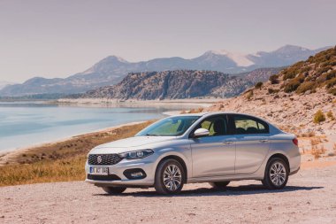 07 Eylül 2020, Burdur, Türkiye: Fiat Egea toprak bir yolda veya çakıl zeminde klasik bir Akdeniz manzarasının arka planına karşı - deniz ve kayalık dağlar