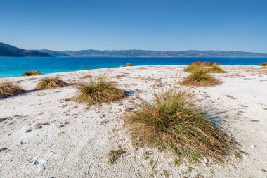 Türkiye 'deki ünlü Salda Gölü üzerinde çimen çalıları olan beyaz kumlu plajın panoramik manzarası. Doğanın harikaları ve Türk maldivleri konsepti