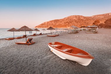 Türkiye 'nin Datca Yarımadası' ndaki Ovabuku plajında güneşli yataklar ve güneş şemsiyeleri tatilcileri bekliyor. Ön planda turist botu