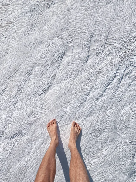 Men\'s feet on white calcite travertines with mineral water from thermal springs in Pamukkale, Turkey. The concept of Spa resorts and health of legs and feet