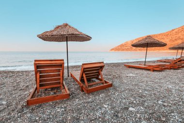 Türkiye 'nin Datca Yarımadası' ndaki Ovabuku plajında güneşli yataklar ve güneş şemsiyeleri tatilcileri bekliyor. Fotoğraf sabah erken saatlerde gün doğumunda çekildi.