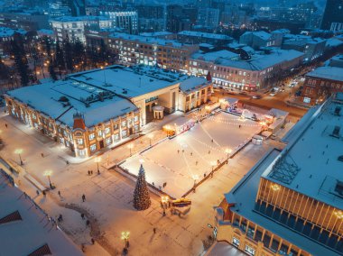 23 Aralık 2020, Ufa, Rusya: Alışveriş merkezinin yakınlarındaki muhteşem bir kış şehrindeki bir Noel ağacının arka planındaki buz pateni pistinde eğlenen ve kayan insanların hava manzarası