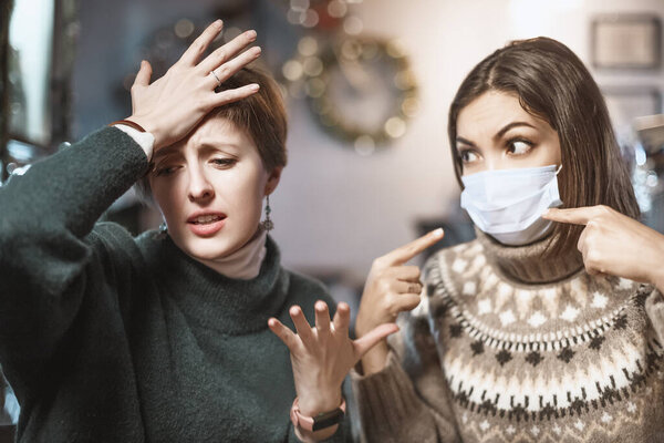 Asian woman in a medical mask argues and fights with her opponent, who does not believe in the coronavirus and the covid-19 pandemic and does not comply with the rules and restrictions.