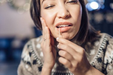 Asyalı bir kadının büyük bir yemekten sonra dişi ağrır ve dişlerindeki boşluktan kürdanla yiyecek kalıntılarını çıkarır. Diş sağlığı ve temizlik kavramı