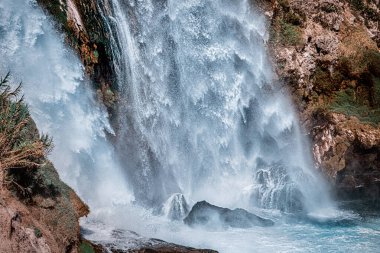 Dik bir uçurumdan denize ya da okyanusa düşen damlaları ve damlaları olan bir şelalenin yakınına..