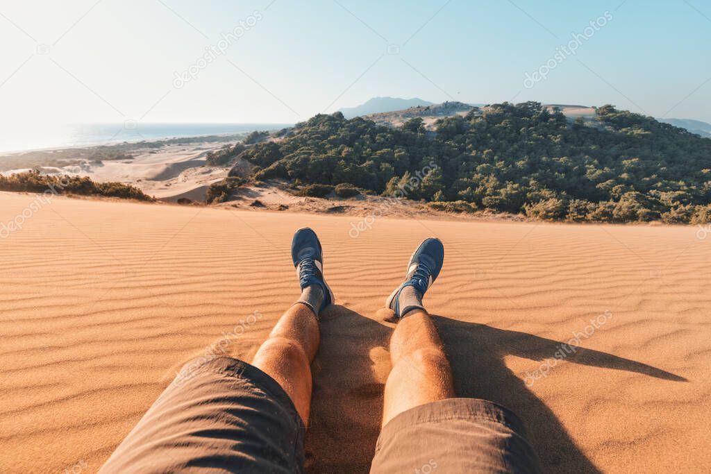 feet of a traveler in shorts and hiking shoes on the background of a paradise landscape with golden sand and blue sea in the background. Lycian Way and footpath trail concept