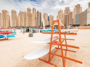Dubai 'deki JBR Sahili' nde sörf ve yemek tahtalarının yanında durup, denizde yüzmek. Su sporları ve eğlence konsepti