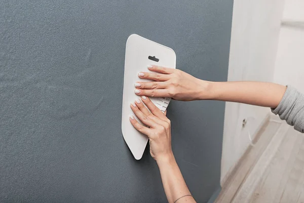 Master hands using a spatula smooth out the bubbles and creases on the whimsical monochrome blue wallpaper on the wall