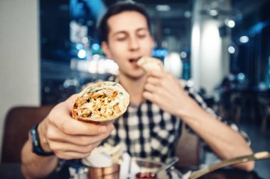 Mutlu Avrupalı adam Yunan jiroskopu ya da Asya shawarması yiyor. Fast food lezzeti et ve sebzeli bir rulo düz ekmektir.