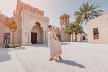 Kırmızı sarıklı ve uzun elbiseli bir kadın turist Bur Dubai ve Creek 'in eski dar sokaklarında yürüyor. Seyahat ve gezi konsepti