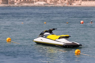 Deniz motosikleti ve su bisikleti kıyıya demirlemiş durumda ve tatil beldesinde tatilcileri ve ekstrem sporcuları bekliyorlar. Su sporları ve eğlence