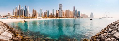 Basra Körfezi 'nin kumlu sahili ve Bluewater Adası' nın geniş manzarası dünyaca ünlü dönme dolabı Dubai gözü ve otelleri ve evleri olan sayısız gökdelenler.