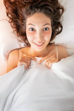 Asyalı kadın göz bandı yapıştırdı ve yatağında uyumaya hazırlandı, böylece sabah hiçbir morluk ve şişlik yoktu.