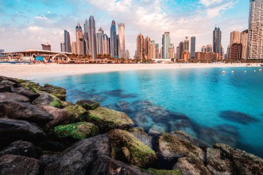 Majestic kayaları, Basra Körfezi 'nin mavi suları ve Dubai' nin liman ve JBR körfezi bölgesindeki renkli gökdelenlerle ön planda dalgalanır.