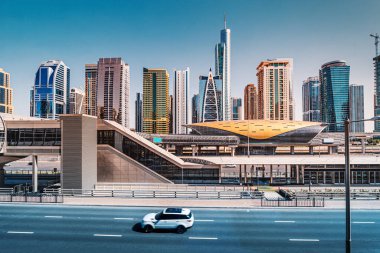 Dubai 'deki ulaşım iletişimi ve karayolu altyapısı - bir yolcu arabası yüksek hızlı bir otoyolda ve metro girişinde ilerliyor