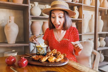 Kadınlar geleneksel bir Gürcistan kırsal restoranında tkemali soslu ızgara tabaka tavukları yiyorlar.