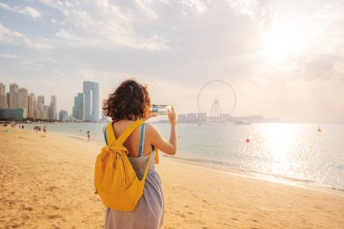 Kadın seyahat blogcusu Bluewaters adasındaki gökdelenlerin sosyal ağları ve Dubai 'deki ünlü Ain Ferris Wheel için fotoğraf çekiyor.