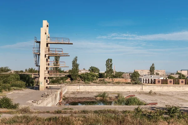 Ruins of a swimming pool with a diving tower reminiscent of Chernobyl.