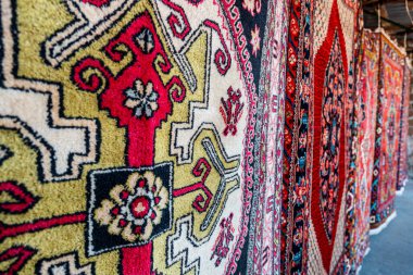 Bir sürü halı güneşte kuruyor. Parlak renkler ve soyut desenler