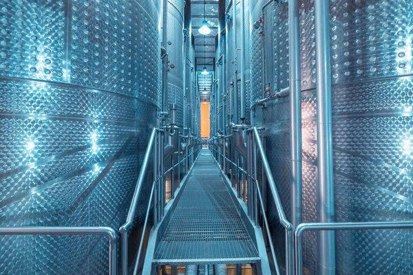 Large metal vats in which wine or beer is fermented at the factory at the winery. Concept of technologies and equipment for the production of alcoholic beverages