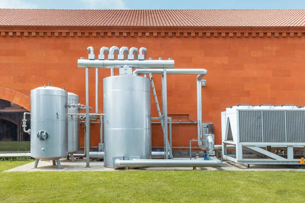 Industrial refrigeration system with compressor and metal tanks outside the wine production plant. Thermovinification and temperature constancy in the cellar.