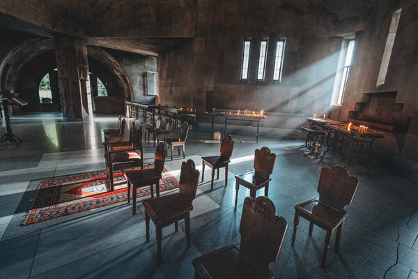 Empty interior of a dark and ancient Armenian church into which a bright beam of light penetrates. The concept of religion and faith