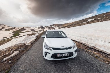 19 Mayıs 2021, Aragats, Ermenistan: Dar ve tehlikeli asfalt yolu kışın yüksek dağlarda esiyor. Yüksek kar yağışı otobanın kenarında kaldı