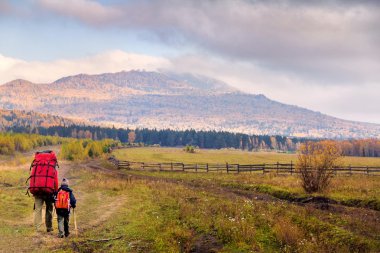 Baba ve oğul dağlarda yürüyüş yapıyor.