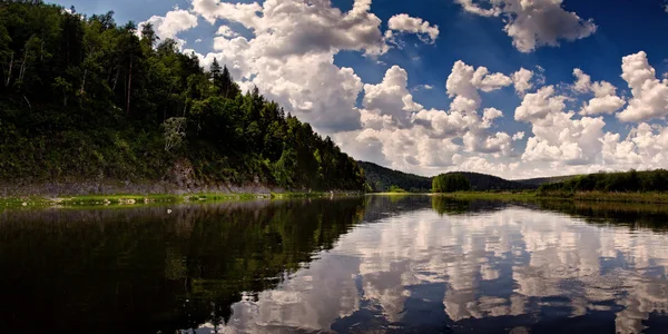 Sjön bland kullarna med reflektioner av moln på himlen — Stockfoto
