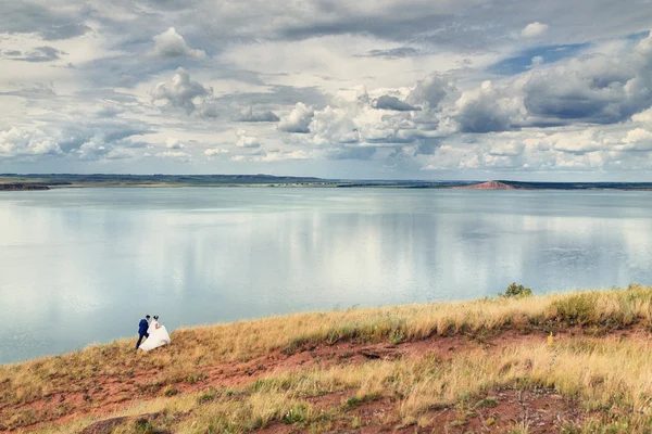 Nevěsta a ženich na břehu jezera — Stock fotografie