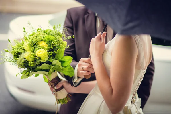 Наречений і наречений з букетом квітів під парасолькою — стокове фото