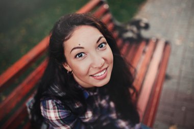 Esmer bir parkta bankta gülümseyen