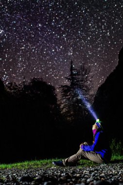 Woman looking at stars with headlamp gleaming clipart