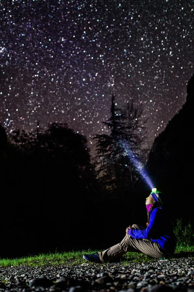 Femme regardant les étoiles avec une lampe frontale brillante — Photo