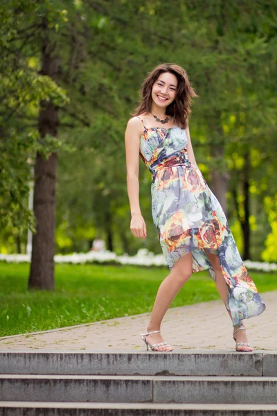 Молодая женщина в парке играет с краем платья — стоковое фото