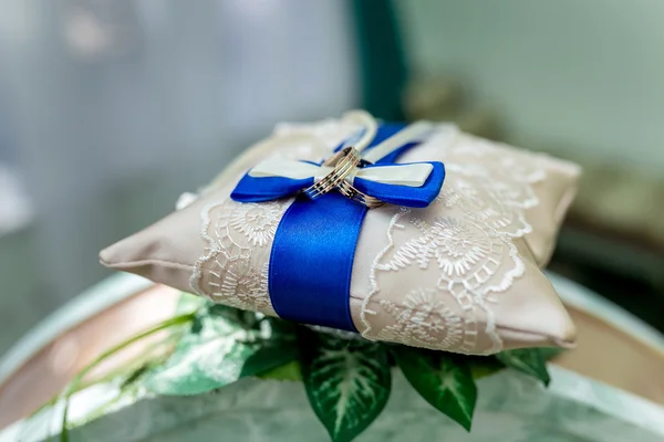 Two gold wedding rings on white and blue lacy pillow — Stock Photo, Image