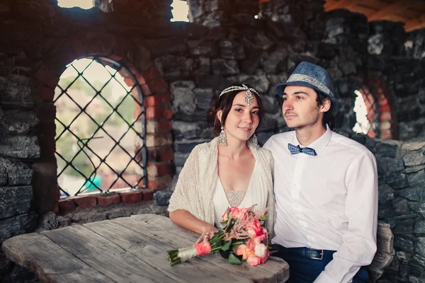 The bride and groom in the castle at a wooden table — Stock Photo, Image