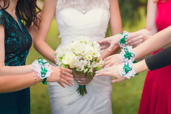 Руки подружки нареченої з браслетами розтягуються до весільного букета — стокове фото