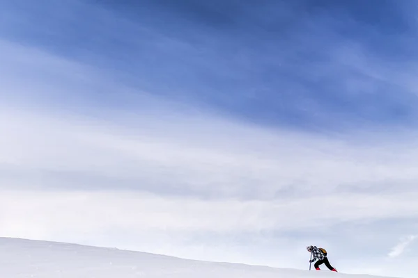 Hiker is climbing on top of the mountain against blue sky in win — Stock Photo, Image