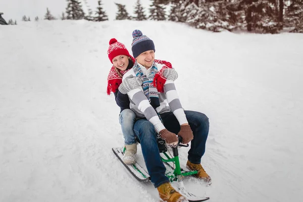 Coppia innamorata slittino nel parco invernale. Vestiti con cappelli a maglia — Foto Stock