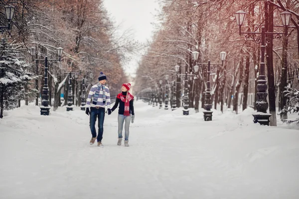 Ett par i kärlek söta tröjor för promenader i parken snöiga vintern. Begreppet alla hjärtans dag — Stockfoto