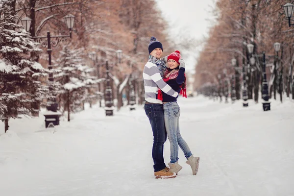 Um casal no amor camisolas bonitos para passeios no parque de inverno nevado. O conceito do dia dos namorados — Fotografia de Stock