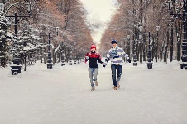 Feliz, jovem casal correndo no parque de inverno nevado . — Fotografia de Stock