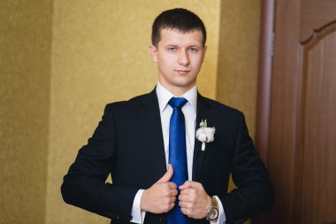 Mutlu yakışıklı damat yaka çiçeği ile siyah elbiseli