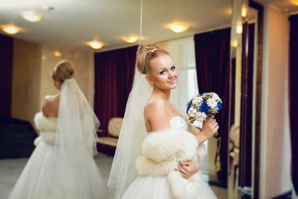 Novia rubia posando en un vestido de novia en el interrior cerca del espejo — Foto de Stock